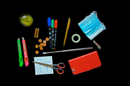 Some office utilities and mouth-nose-mask on a black desk slab