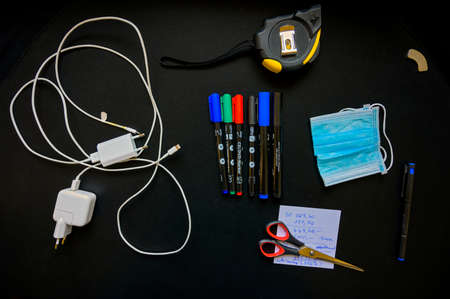 Some office utilities and mouth-nose-mask on a black desk slab