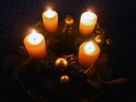 Advent wreath with four glowing candles and golden decoration in the darkの写真素材