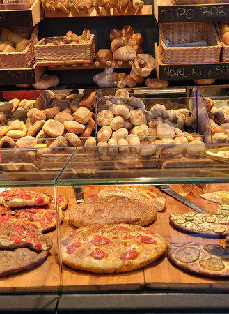 Assortment of baked goods including focaccia and bread rolls in a bakery shop in Puglia, Italy.の写真素材