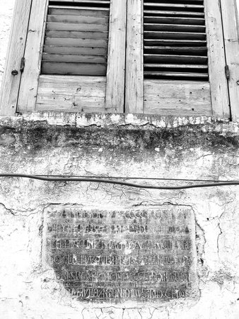 Black and white photo of window shutters with Antique Inscription on Building Facade in Puglia, Italyの写真素材