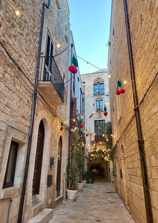 Charming narrow street in Puglia Southern Italy, line historic buildings featuring balconies and ornate Baroque-style window frames. Festive street decorations hanging cherries.の写真素材