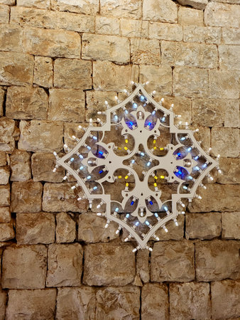 Decorative festival lights hanging on a historic stone wall in Puglia, Italy â traditional Mediterranean village celebration with rustic charm and cultural heritageの写真素材