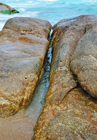 Water spilling over the rocks on the coast - Thailandの写真素材