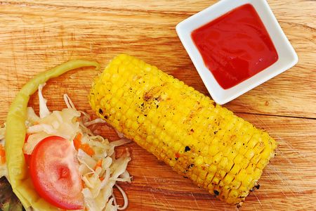 Grilled corn with vegetables on a wooden cutting boardの写真素材