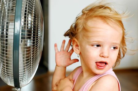 A little girl standing in front of fanの写真素材