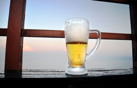 A glass of cold beer and the sunsetの写真素材