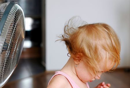 A little girl standing in front of fanの写真素材