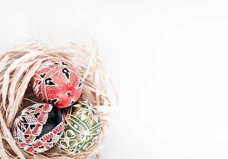 Three easter painted eggs in the nest .