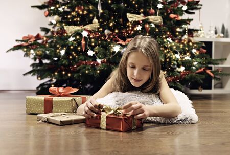 The girl lying near the Christmas tree with giftsの写真素材