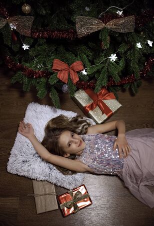 The girl lying near the Christmas tree with giftsの写真素材