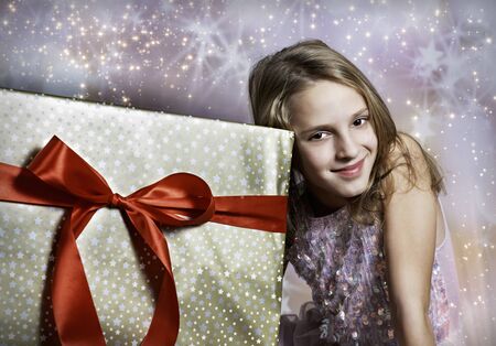 Blonde girl and her big gift with red bowの写真素材