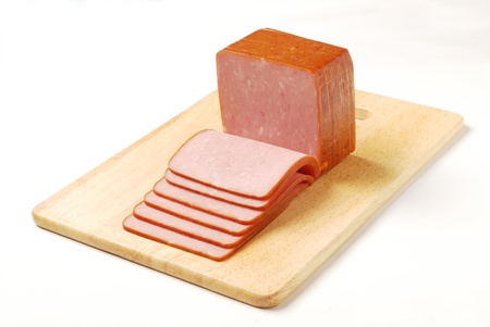 Slices of ham on a wooden board.        