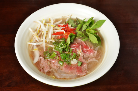 Traditional Vietnamese beef soup pho on a wooden table