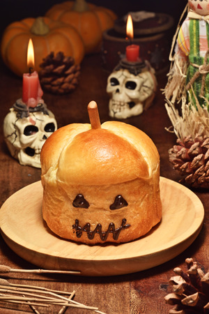 Halloween pumpkin style bread on wooden tableの写真素材
