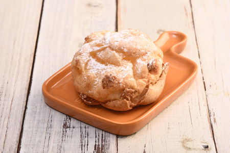 Fresh cream puff on a plate on the table.