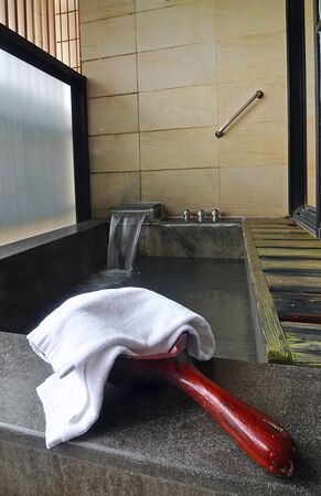Wooden water scoop with a towel in bathroom