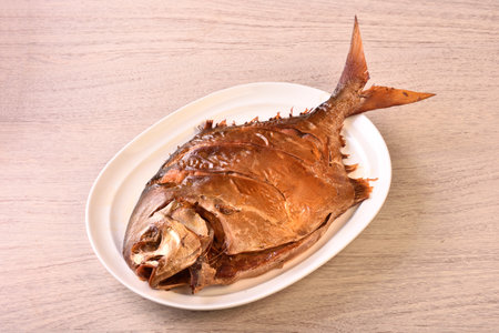 Smoked golden pomfret on white plate. (the Chinese words is'make money, lucky', not a logo or trademark.)の写真素材