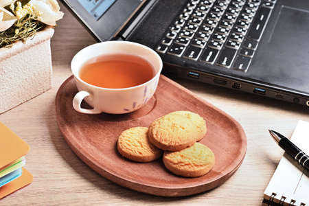 Coconut cookies with tea on the wooden tray in officeの写真素材