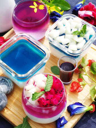 Butterfly pea flower milk jelly topped with fruit and mint in glass jarsの写真素材