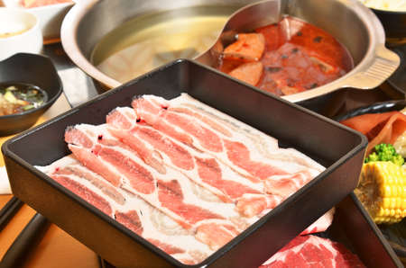 Raw pork in the dish wait to get down boiling in hot potの写真素材