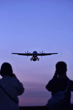 plane landing to airport runway at sunsett, two silhouettes of people
