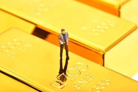 Miniature people figure businessman stand on pile of gold bar.の写真素材