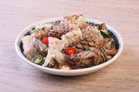Cold fish skin in sauce in a bowl on a wooden tableの写真素材