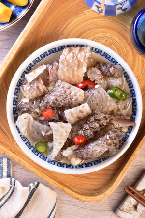 Cold fish skin in sauce in a bowl on a wooden tableの写真素材