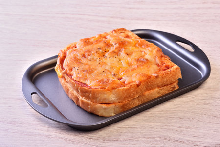 Pizza toasted bread with tomato sauce on a black plateの写真素材