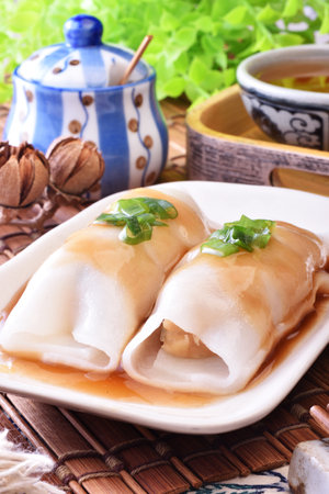 Steamed rice rolls with fresh prawn filling served in a dish on wooden tableの写真素材