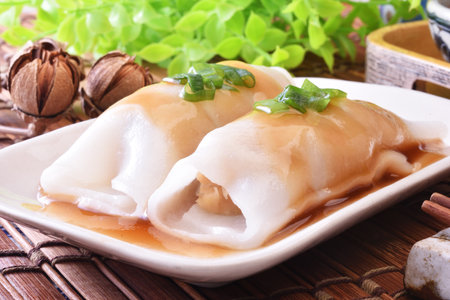 Steamed rice rolls with fresh prawn filling served in a dish on wooden tableの写真素材