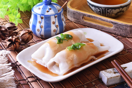Steamed rice rolls with fresh prawn filling served in a dish on wooden tableの写真素材