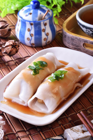 Steamed rice rolls with fresh prawn filling served in a dish on wooden tableの写真素材