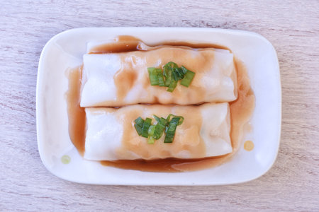 Steamed rice rolls with fresh prawn filling served in a dish on wooden tableの写真素材