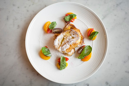 French toast with honey, orange and mint on a white plate.の写真素材
