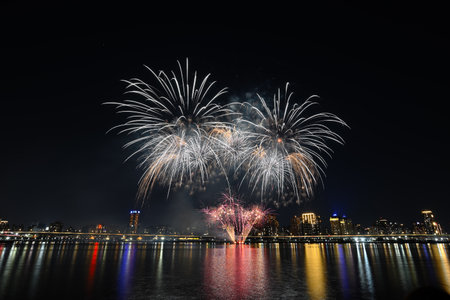 Colorful fireworks of various colors over night sky with reflection in water