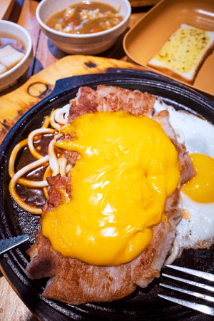 Fried pork chops with melted cheese,pasta and fried egg closeup on iron plateの写真素材