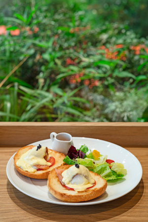 Avocado toast with eggs benedict,smoked salmon,hollandaise sauce and mixed greens on a white plate.の写真素材