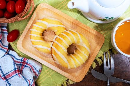 Donuts on a wooden plate with a cup of tea on the tableの写真素材