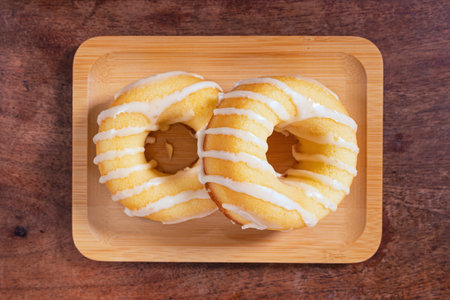Donut on wooden plate on wood background. Top view with copy space.の写真素材