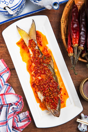 Steamed fish with chili sauce on a white plate on wooden backgroundの写真素材