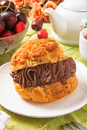 Choux cream with chocolate and cherry on a plate. Selective focus.