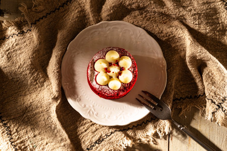 Red velvet cake with cream on a white plate on a wooden backgroundの写真素材