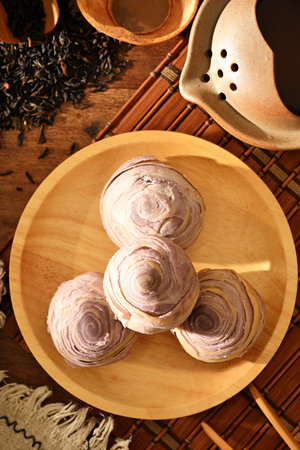 Taro cake on wooden plate and tea setの写真素材