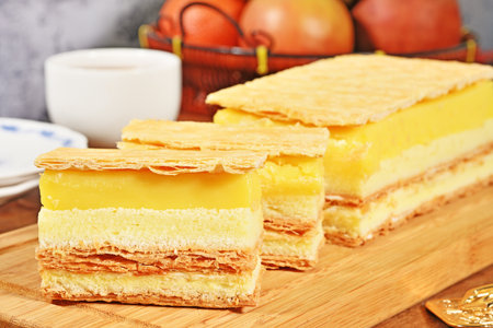 Slice of lemon napoleon cake on a wooden cutting board, selective focusの写真素材