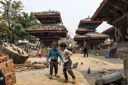 Unitendified kids are feeding pigeons with dry corn at Durbar Square in Bhaktapur after major earthquake in 2015, Kathmandu, Nepalのeditorial素材