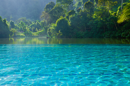 Swimming pool beside lake - Swimming pool at lake side covering by jungle treeの写真素材