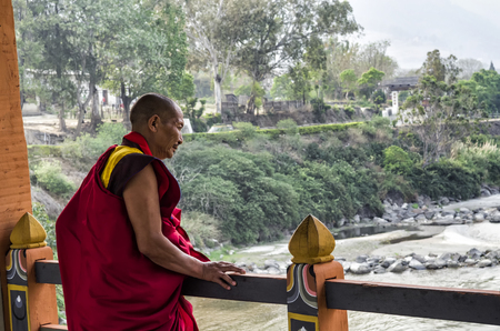 An unidentified buddhist monk with traditional robes resting and looking to the river at the Punakha Dzong or Pungthang Dewachen Phodrang monastery, Punakha, Bhutan.のeditorial素材