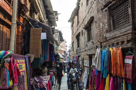 Visitors walking and trading along historic busy narrow street around Bhaktapur that was partially destroyed at major earthquake in 2015, Bhaktapur, Nepalのeditorial素材